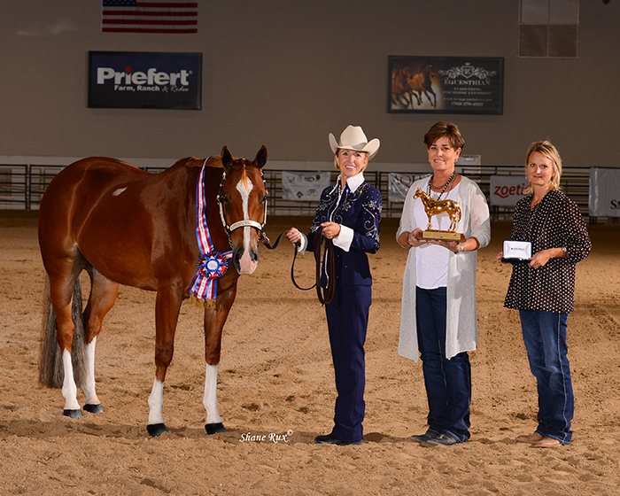 Marian (left) and "Ace" accepting their championship prizes: a ribbon, trophy, and buckle. Also pictured is Ace's trainer and breeder.